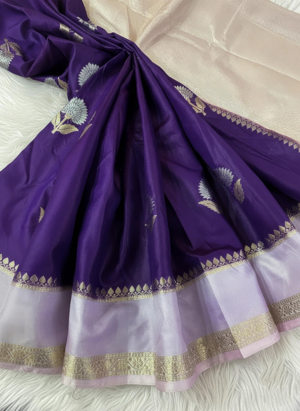 Purple saree with gold border on a white fabric background